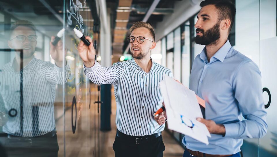 two men looking at whiteboard